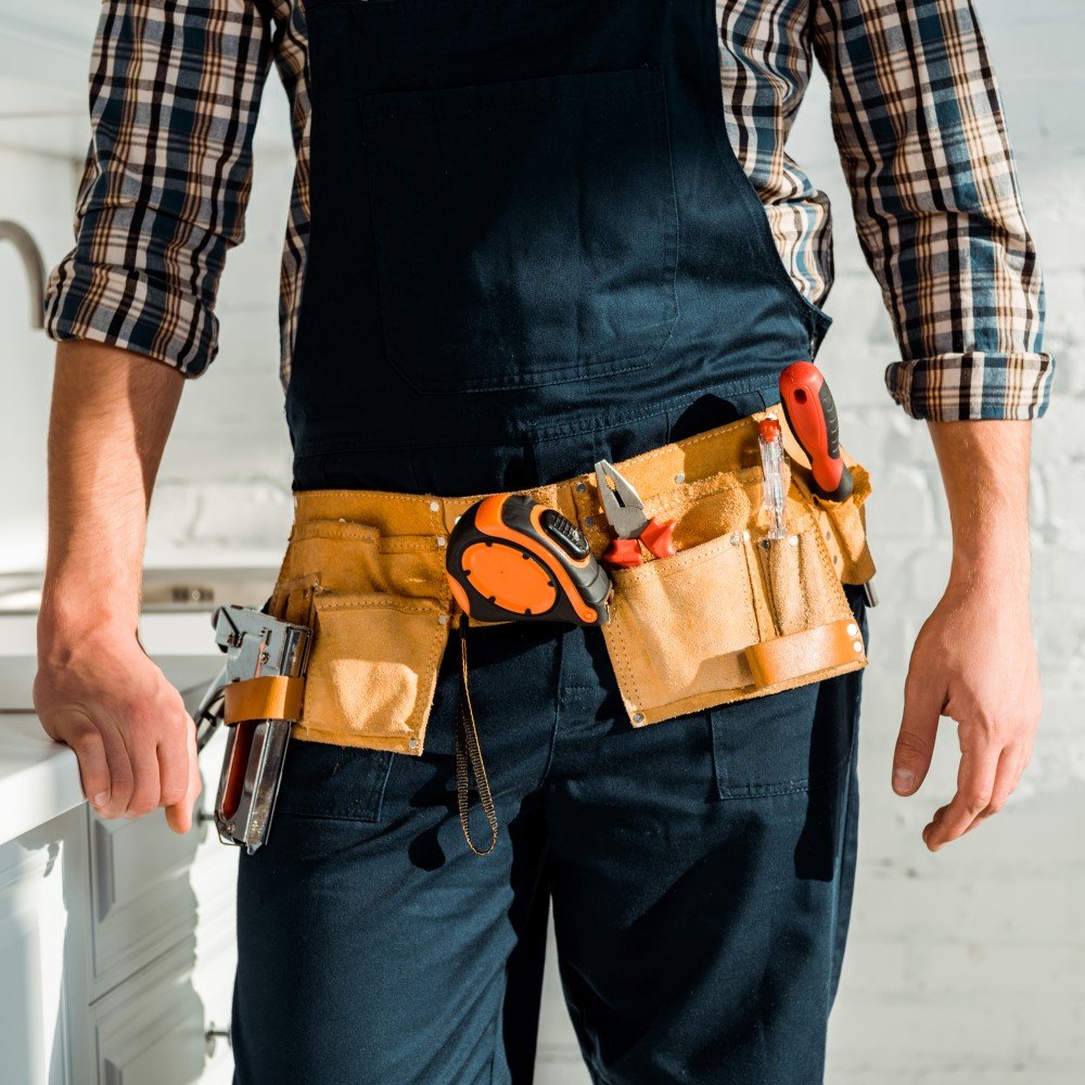 Home-service technician wearing tool belt standing in a customer’s home