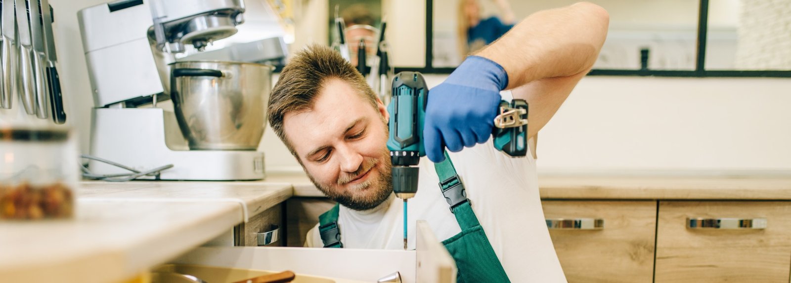 Home service technician drilling and installing hardware in a residential kitchen